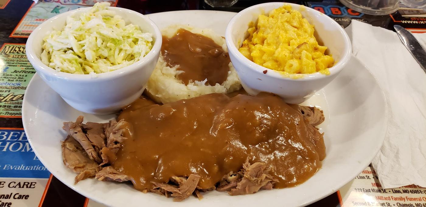 Sliced roast beef under gravy with mashed potatoes, coleslaw and macaroni cheese.